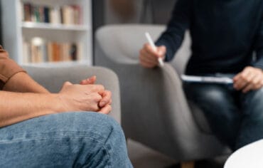 woman with hands together talking with counselor